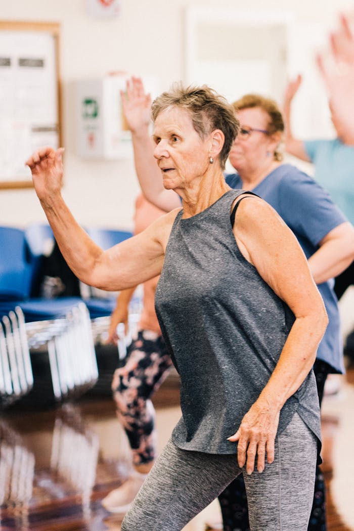 Elderly Woman in Gray Tank Top and Leggings Exercising